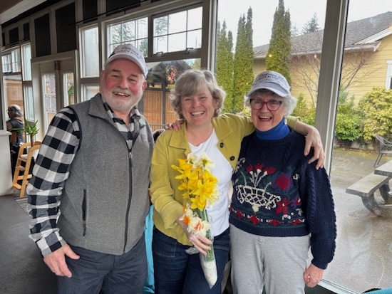 Three people posing for photo and smiling holding daffodils