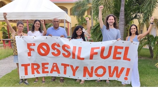 A group of people holding up a huge banner that says "Fossil Fuel Treaty Now!"