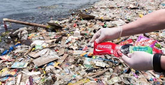 Plastic waste on the shore - and someone holding a Coca-Cola label