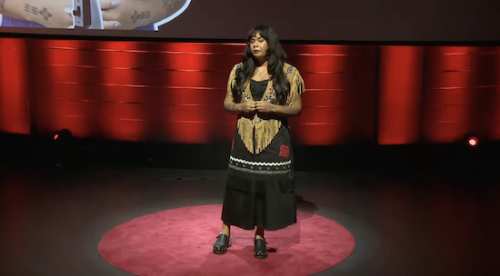 An Indigenous woman on stage talking