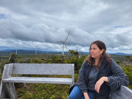 Kara Wilson sitting on a bench with wind turbines in the background